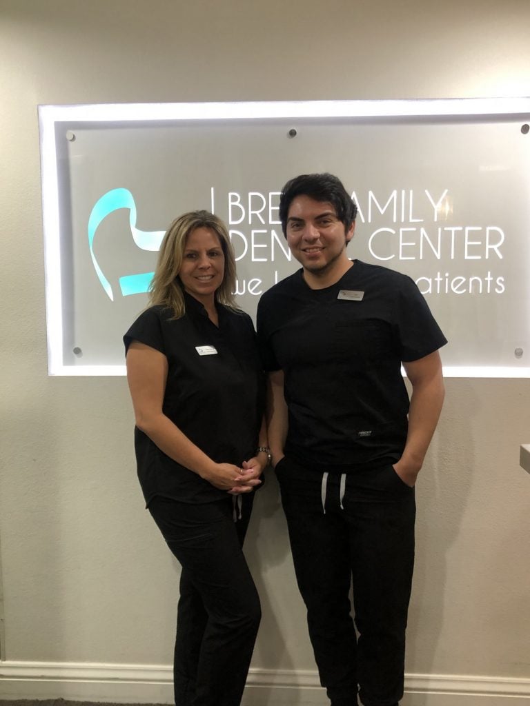 two administrators posing in front of the logo